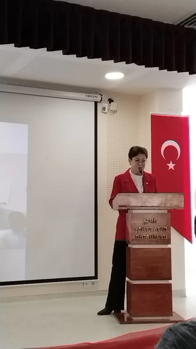 Melek Kener okul konferansında kürsüde konuşma yapıyor